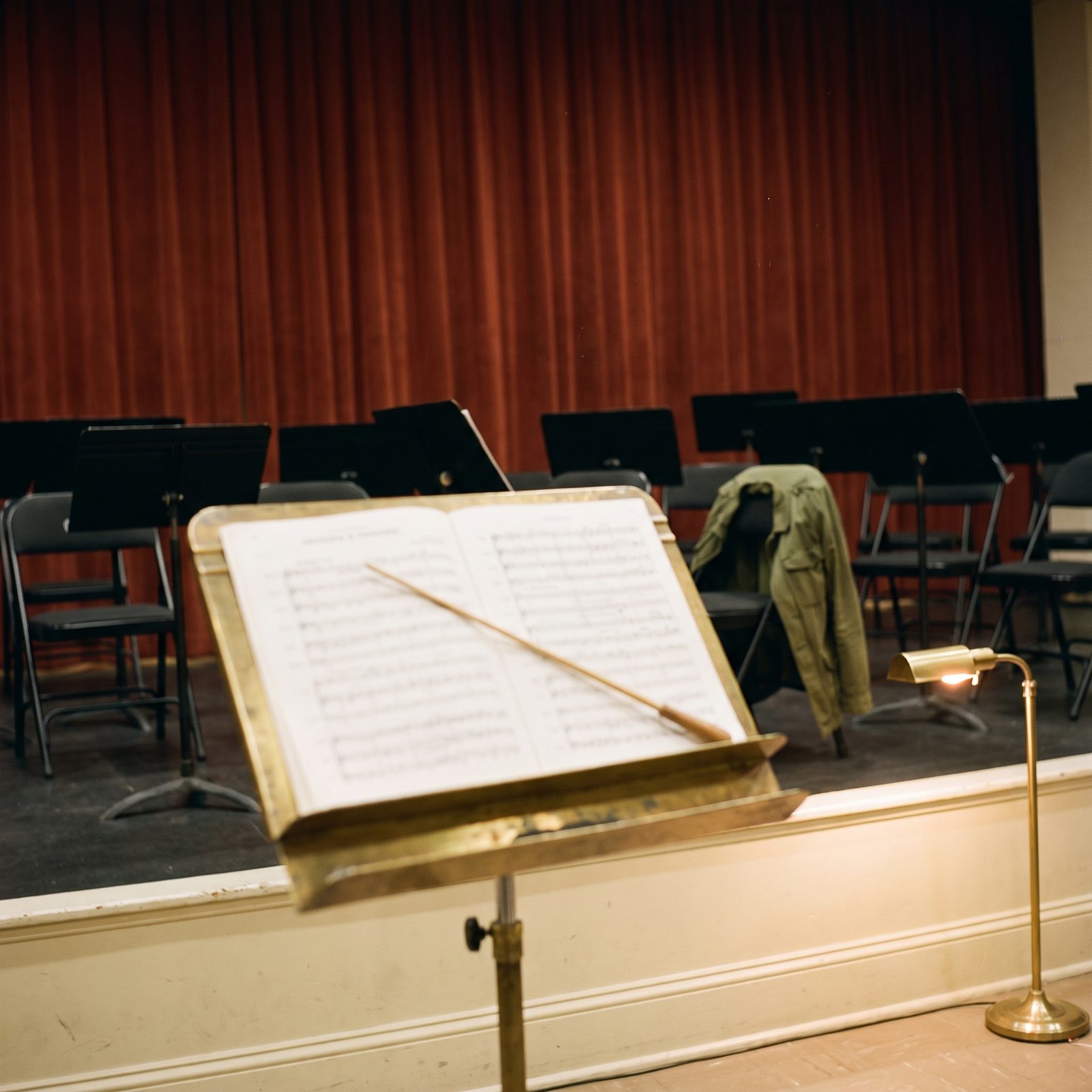 The conductor's stand, with a baton resting on the score before the musicians' empty chairs