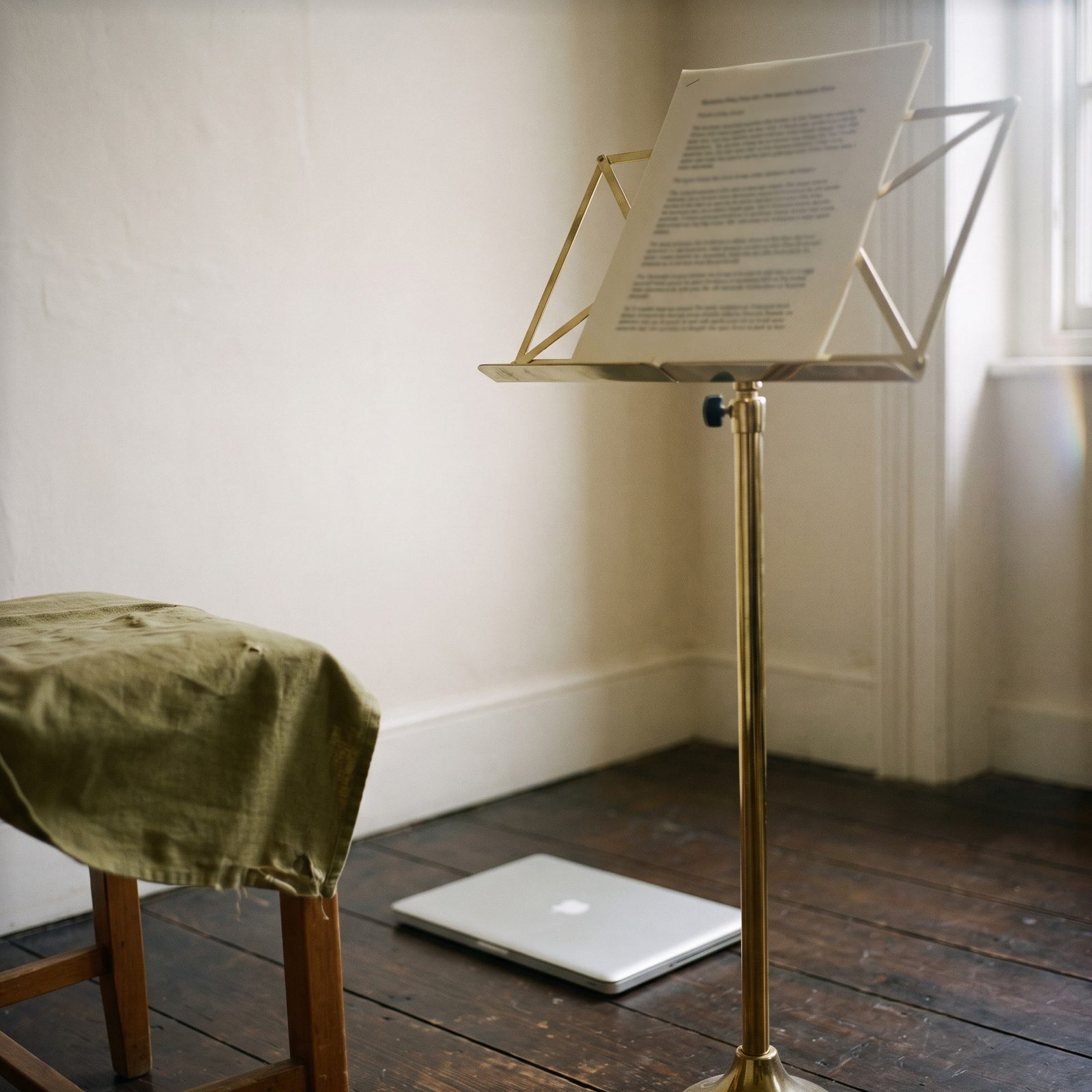 Un pupitre de musicien en laiton porte un document imprimé, un portable fermé posé au pied